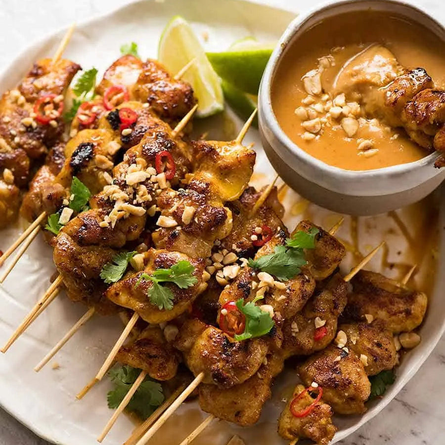 Brochetas de pollo satay tailandesas con salsa de cacahuate servidas en plato - La Despensería