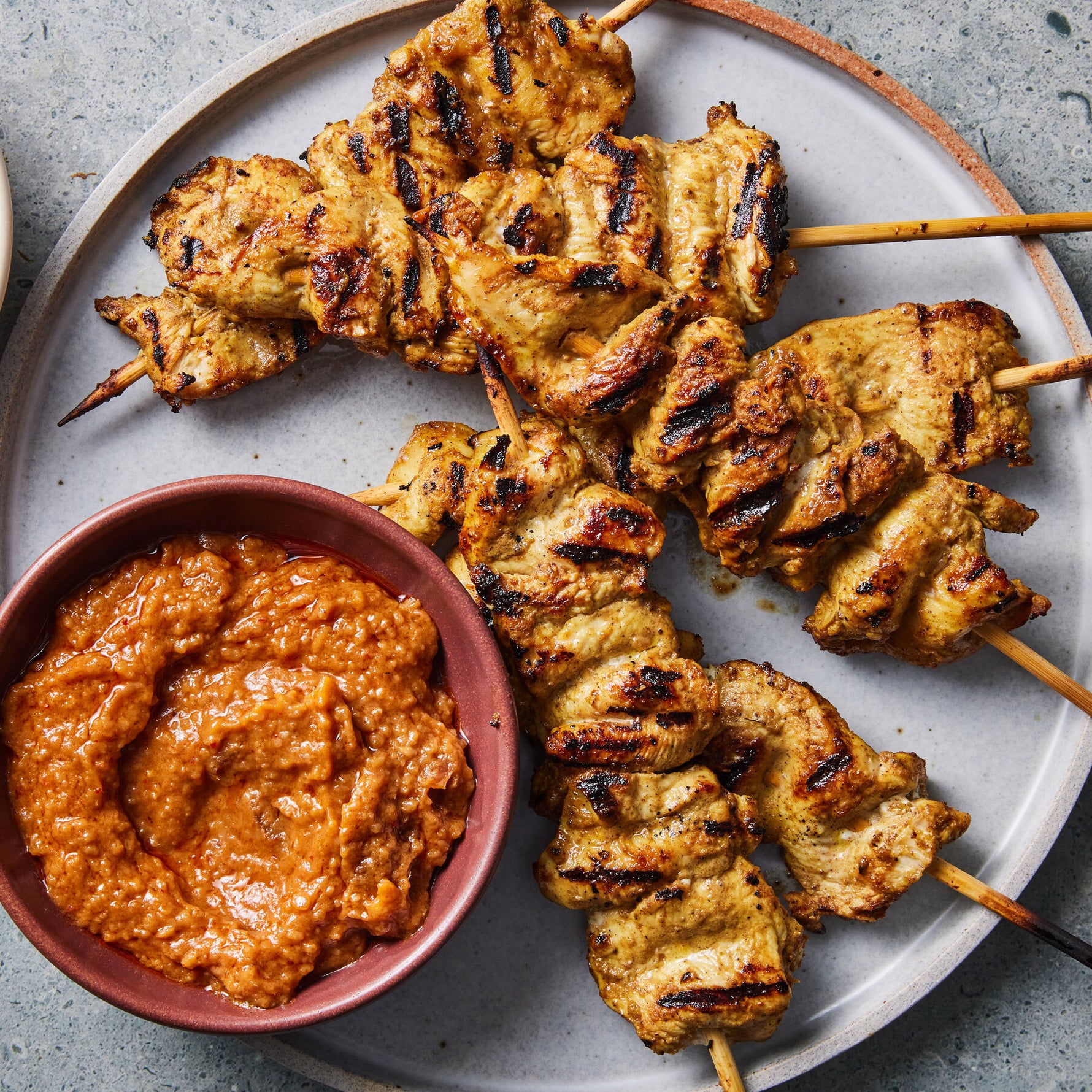 Brochetas de pollo satay tailandesas con salsa de cacahuate servidas en plato - La Despensería
